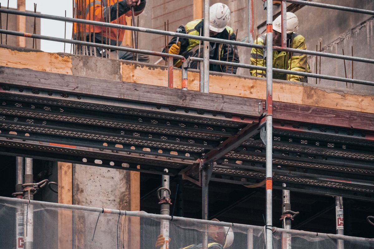 Workers on a scaffolded upper floor setting timber formwork and steel decking for the next slab